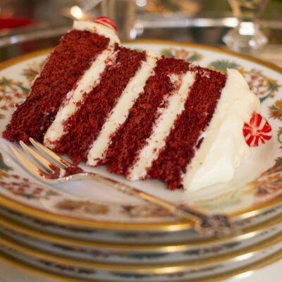 A slice of Peppermint Red Velvet Cake on a Haviland Haute Epoque Dessert Plate with a Christofle Renaissance dessert fork, both from Replacements, Ltd, on a holiday dessert table
