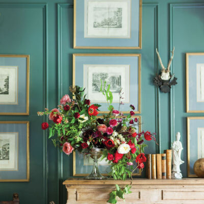 Floral design by Amy Osaba in an antique silver compote against a teal blue wall