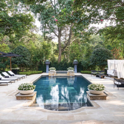 elegant pool and patio area furnished with outdoor seating and potted plants