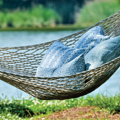 Four pillows piled on an outdoor hammock beside a lake