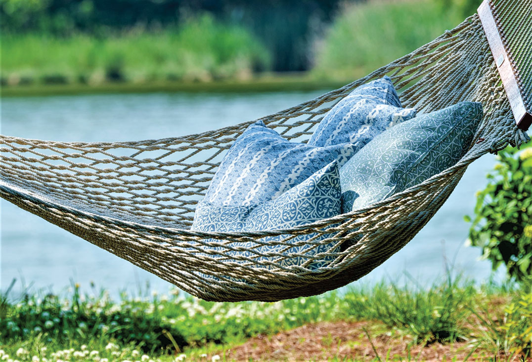 Four pillows piled on an outdoor hammock beside a lake