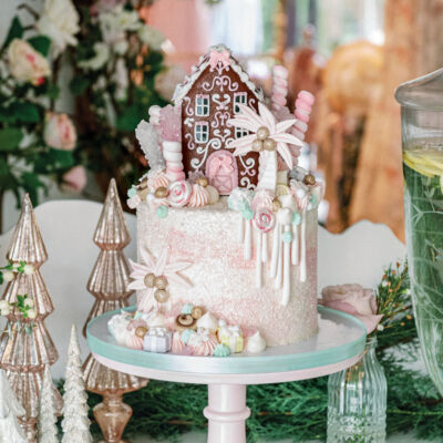 fanciful gingerbread house-topped cake on a pedestal at the Palm Beach Lately and LoveShackFancy holiday party