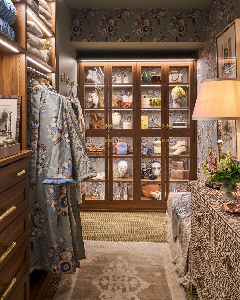 walk-in closet with custom organization unit on back wall, with glass fronted doors displaying the items inside