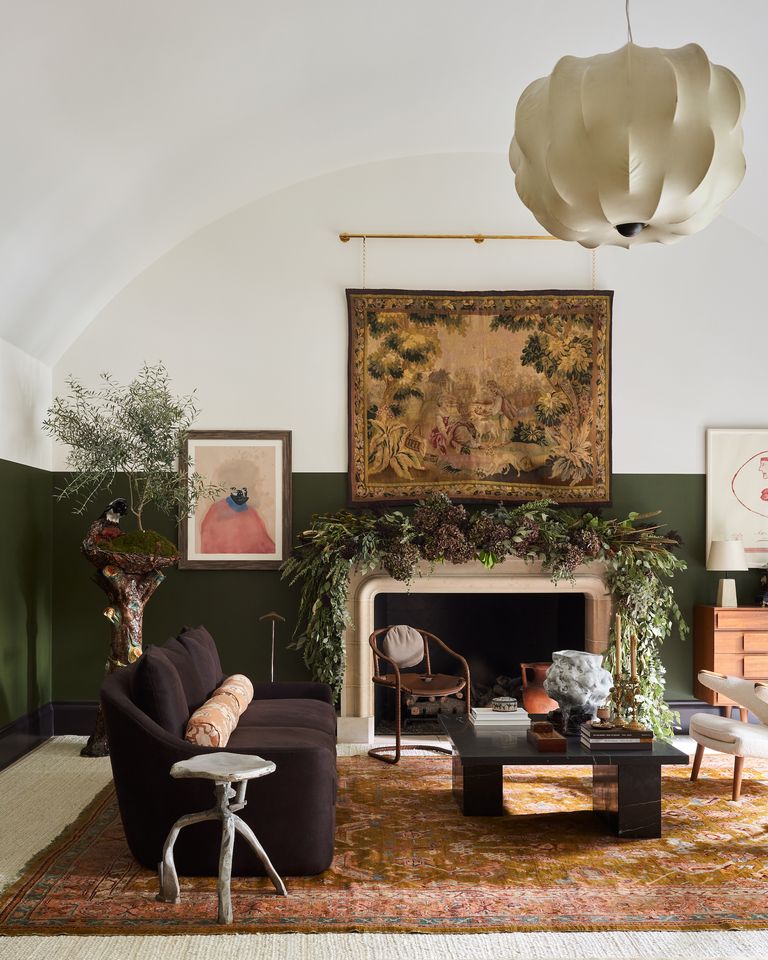 Large room with an arched ceiling painted white, dark olive green walls, dark velvet seating, and an antique tapestry hanging above the mantel, decorated by Michael Viviano for the Kips Bay Showhouse Dallas 2020.