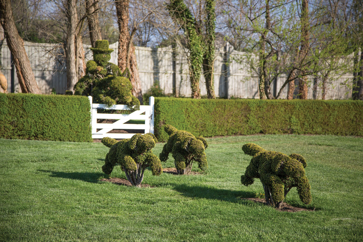 three topiaries depicting a trio of hunting dogs running