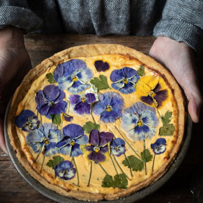 Savory baked cheese tart covered with pressed pansies, an edible flower