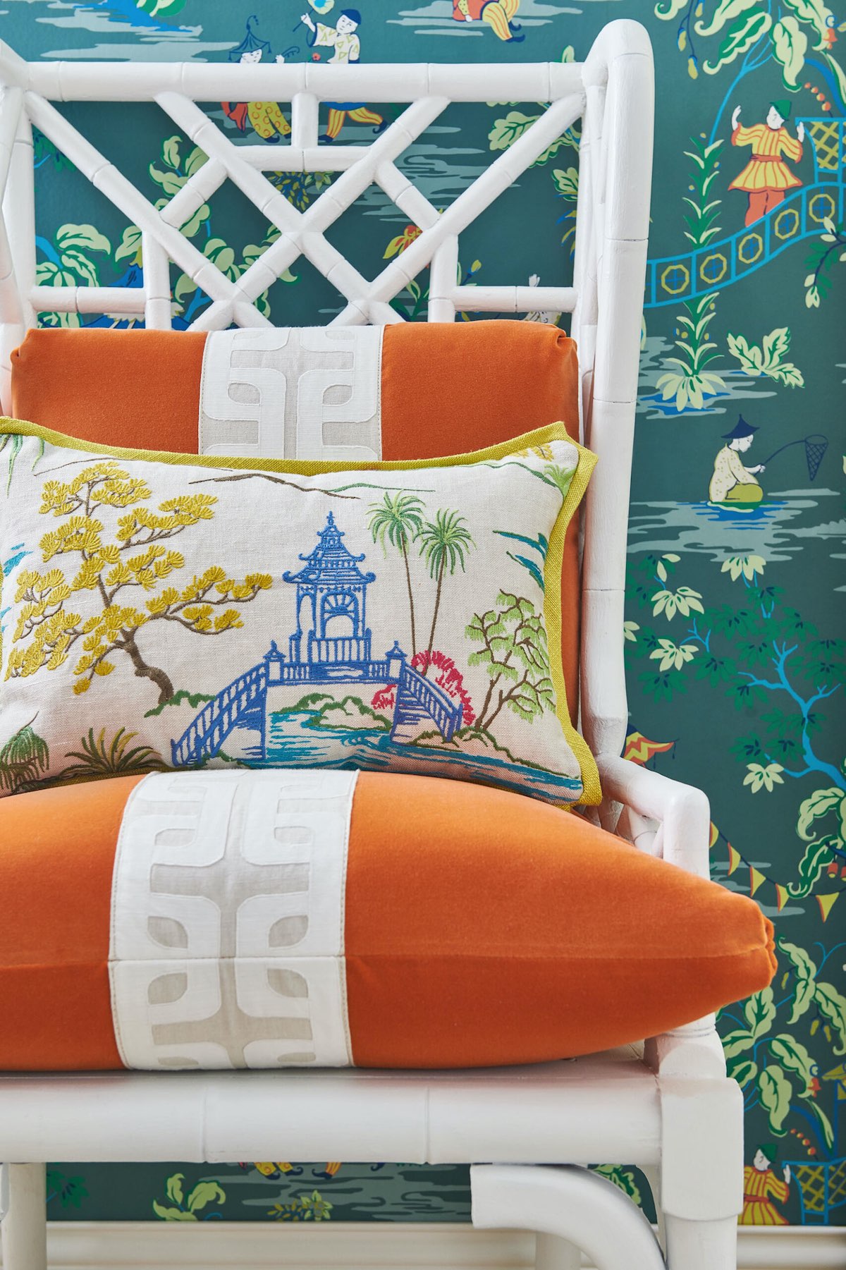 White Chinese-style chair with orange cushions and chinoiserie patterned pillow.