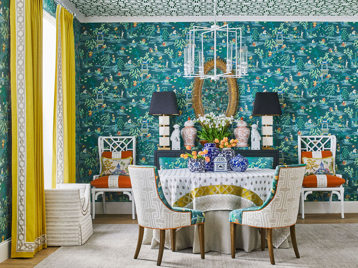 Vibrant dining room featuring teal botanical wallpaper, bright yellow curtains, chinoiserie and geometric patterns from the Stroheim Color collection
