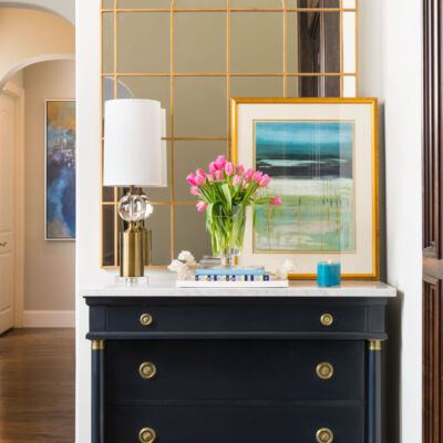 hallway vignette with chest, mirror, lamp, and artwork
