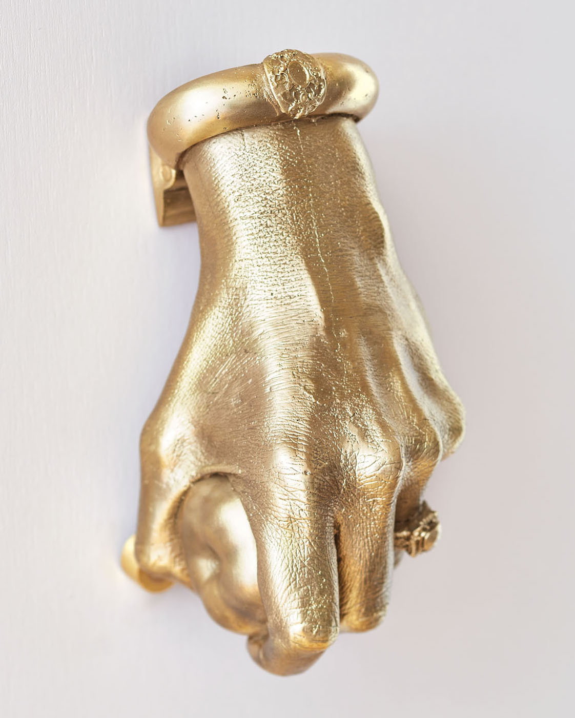 Brass door knocker shaped like a hand holding a pear