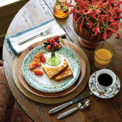 breakfast of toast, berries and granola, and sliced peaches set on a rustic wooden table
