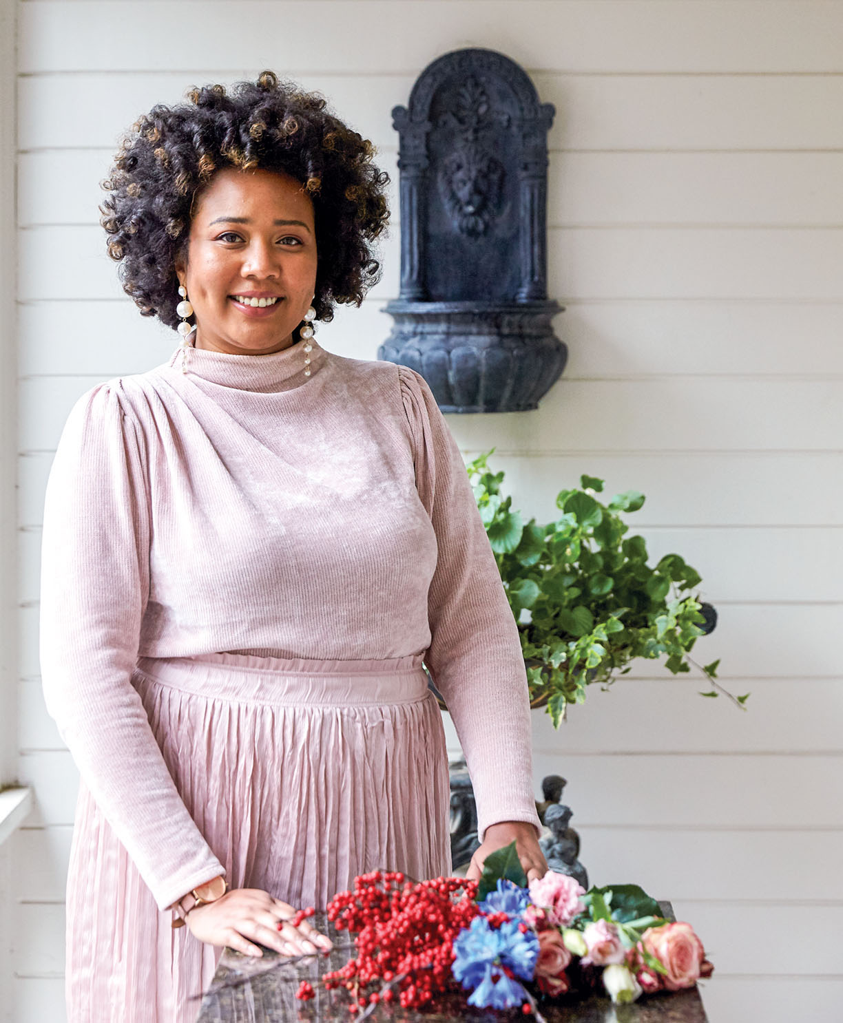Portrait of Erin McClendis, owner of E. Vincent Floral Design, wearing a pale pink sweater and long matching skirt
