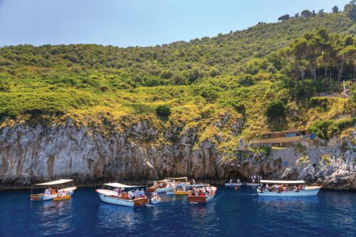 2F762GN Tourists waiting to enter the Blue Grotto (Grotta Azzurra) by rowing boat on the Island of Capri, Italy, Amalfi Coast