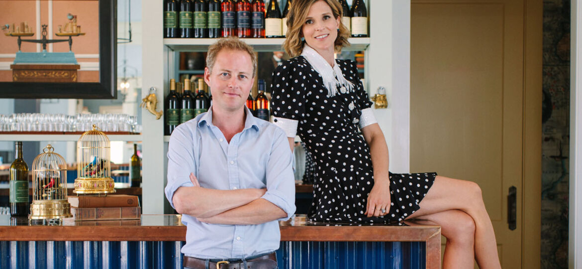 Elizabeth and Guy Pelly, owners of Merrie Mill Farm & Vineyard, pose by the bar of the eclectic wine-tasting room. The bar base is corrugated metal painted bright blue and the bartop is copper.