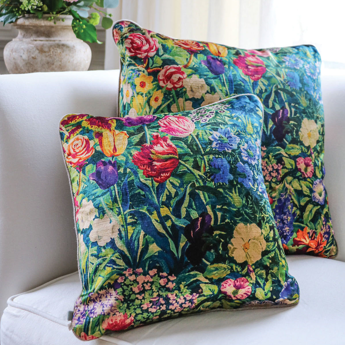 A pair of Velvet Linen's vibrant floral velvet throw pillows on a white linen sofa