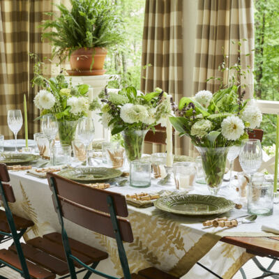 Table set with green and white table cloth, and flower arrangements