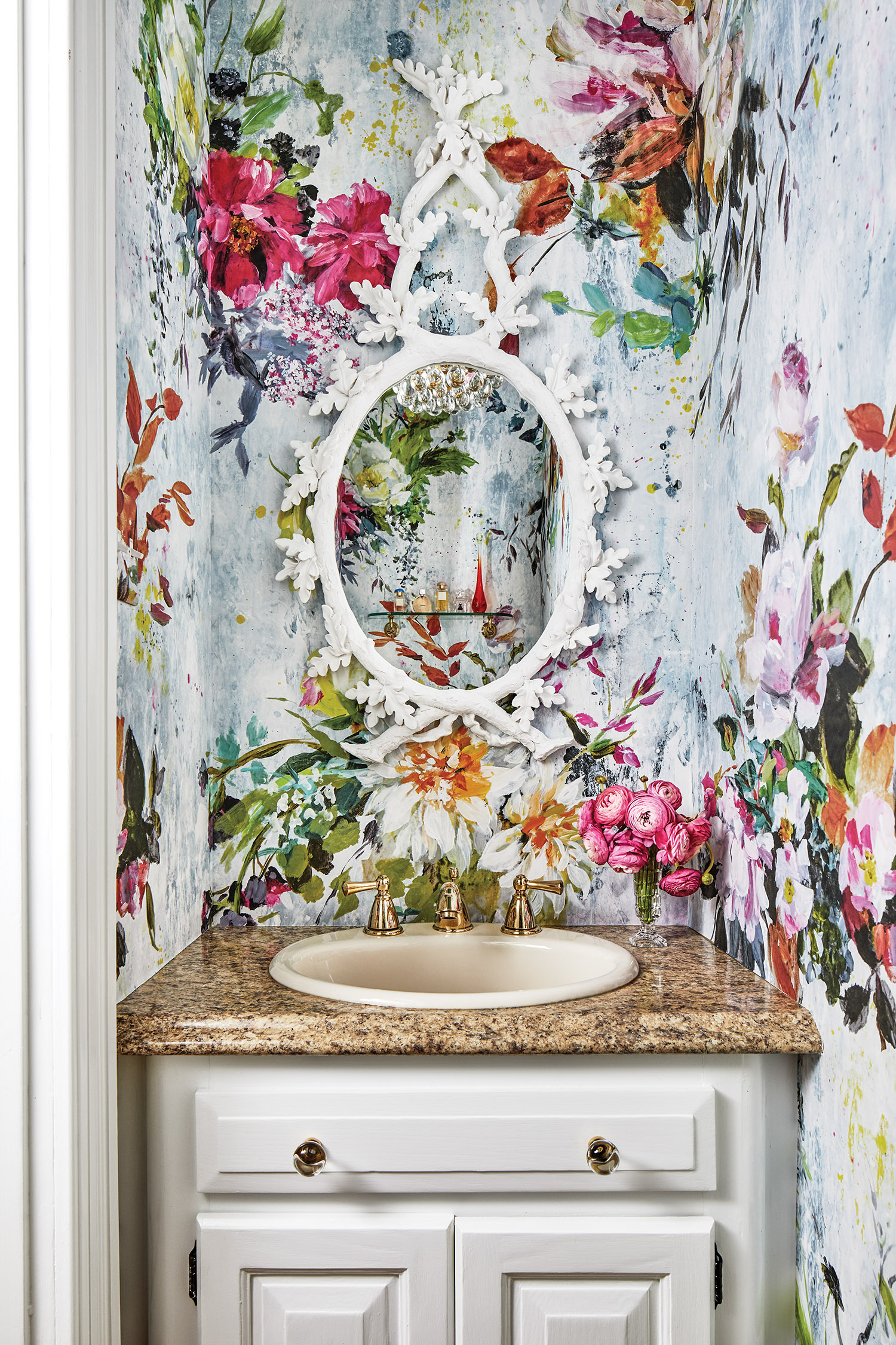 Powder room with a bold Aubriet floral wallpaper from Designer's Guild over the sink.