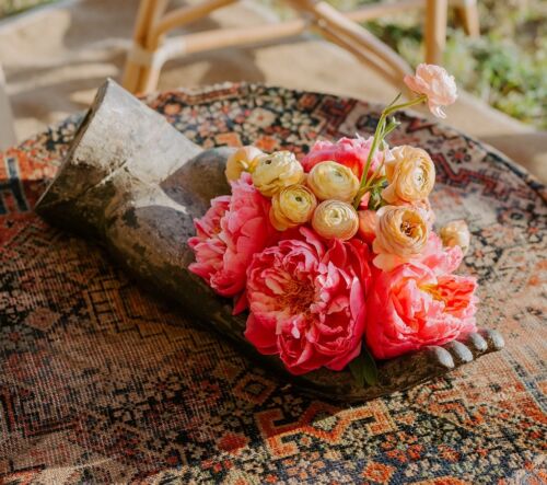 cast-iron sculpture hand with arrangement of peonies and ranunculus