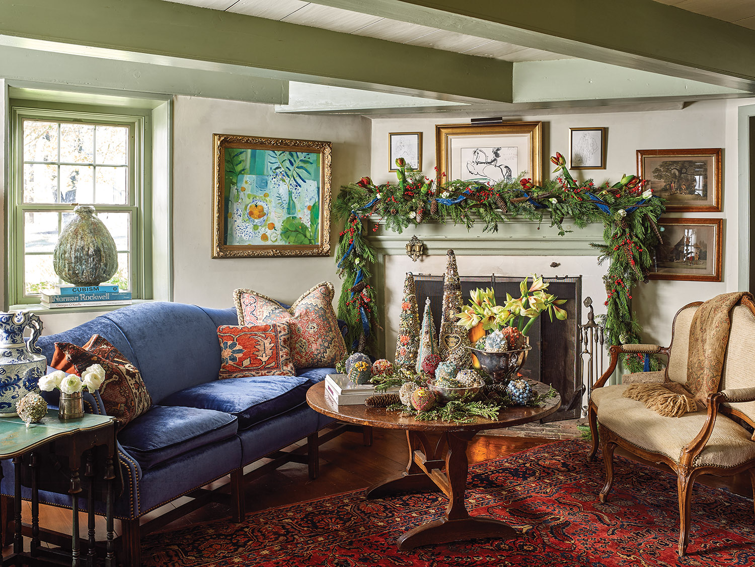 Cara Brown's farmhouse living room decorated for Christmas with garland on mantel and homemade ornaments and arrangement of amaryllis on table.