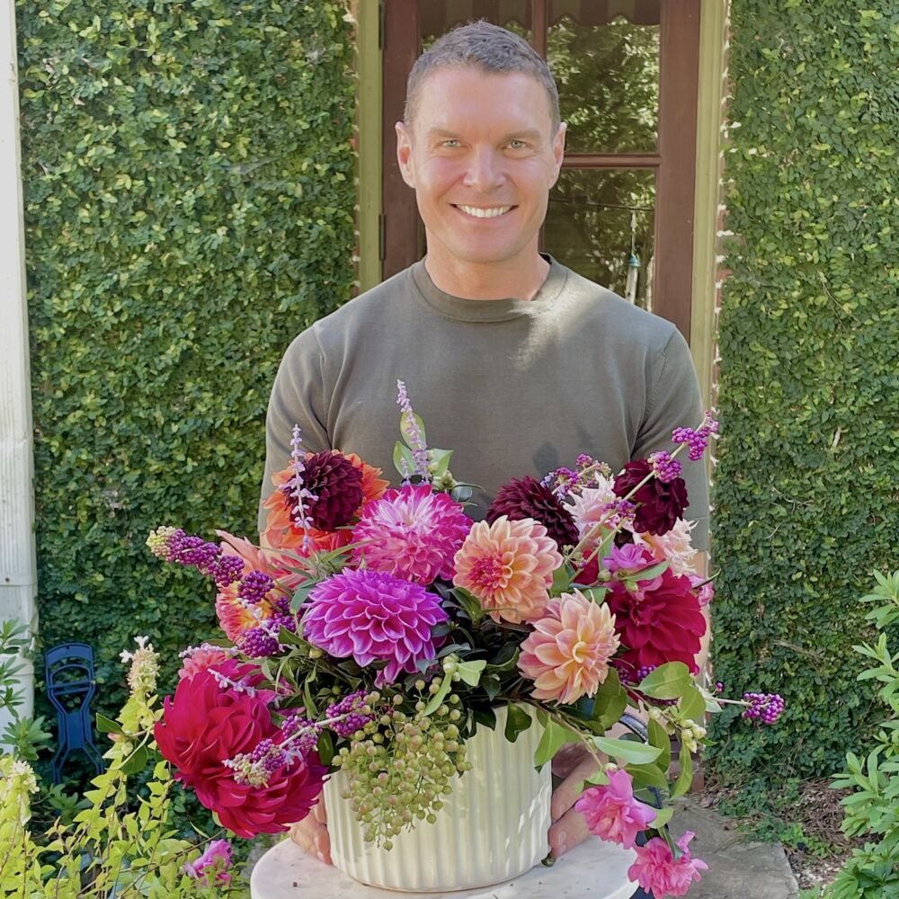 Lewis Miller with arrangement of dahlias, berries, and camellias.