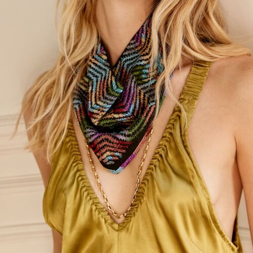 Decolletage of woman wearing beaded scarf and gold necklace