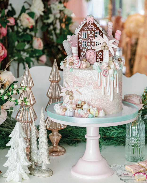 Fanciful gingerbread house-topped cake on a pedestal at the Palm Beach Lately and LoveShackFancy holiday party