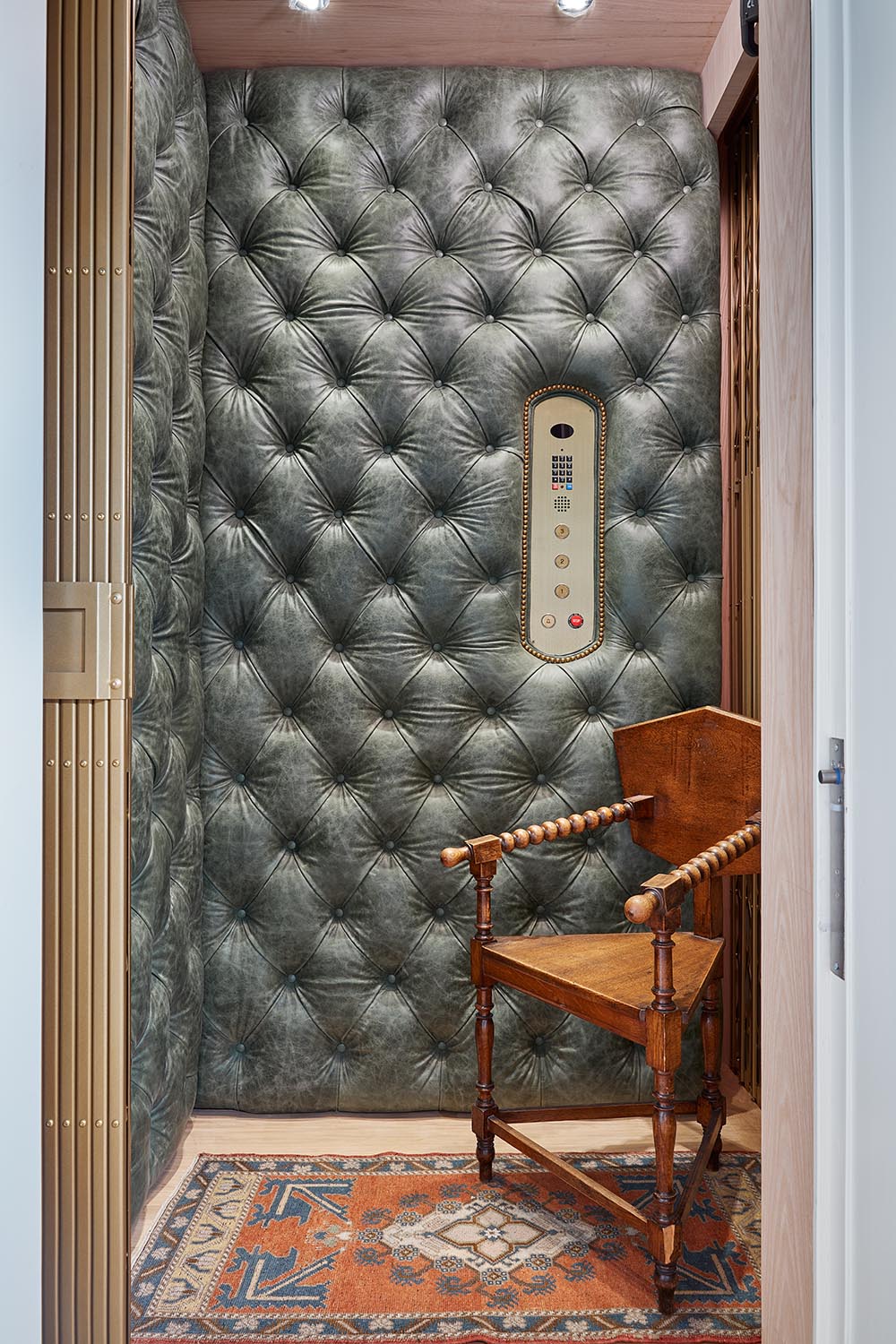 Green, tufted leather covers the walls of the elevator designed by Jared Hughes at the Flower Atlanta Showhouse. An antique chair and rug are in the elevator.