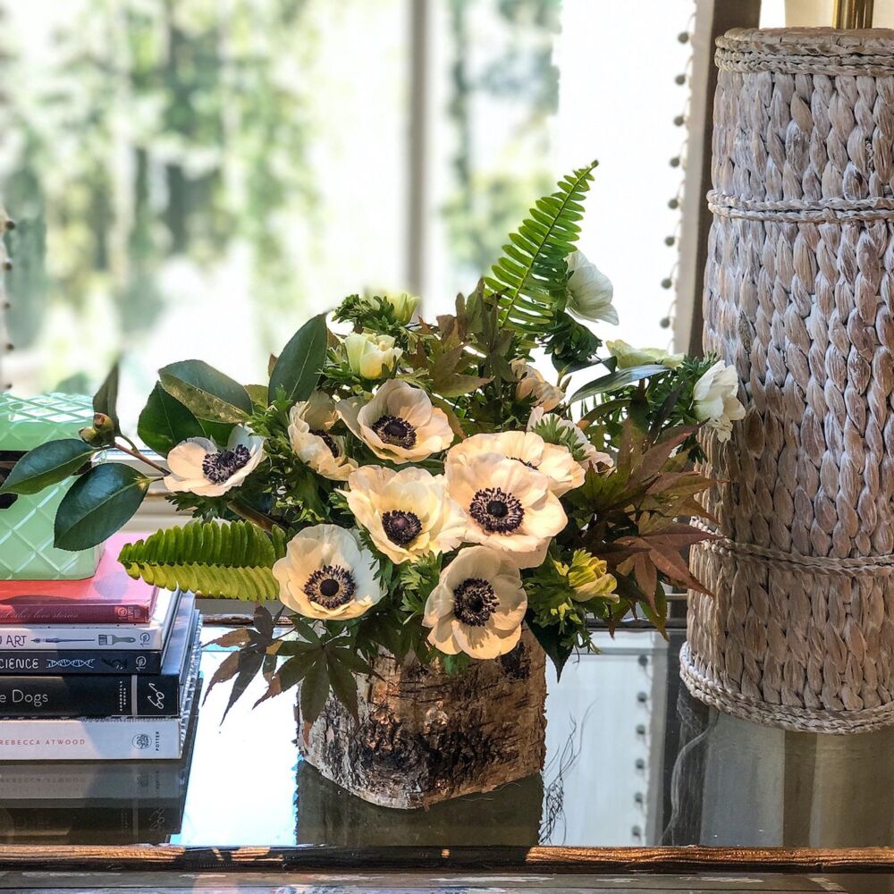 Arrangement of black and white anemonies, fern fronds, Japanese maple foliage, and camellia branches designed by Holly Bryan. On bedside table in Tammy Connor designed room.