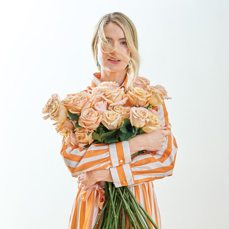 Alice Callahan Thompson wearing orange striped dress, holding bunch of peach roses.