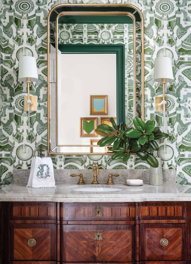 A green wallpaper mimicking the map of a garden covers a powder room with an antique vanity.