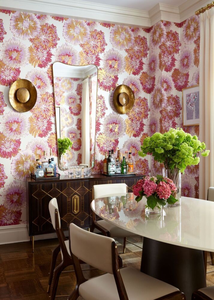 Dining room with pink and gold Frances wallpaper by Philip Gorrivan, vases of green viburnum and pink hydrangeas on table.