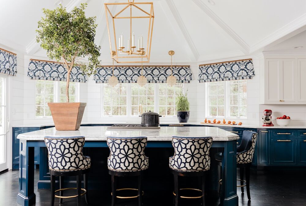 Oversized brass lantern over the island in a blue and white kitchen Three smaller, round pendants over the sink in a large bay window.