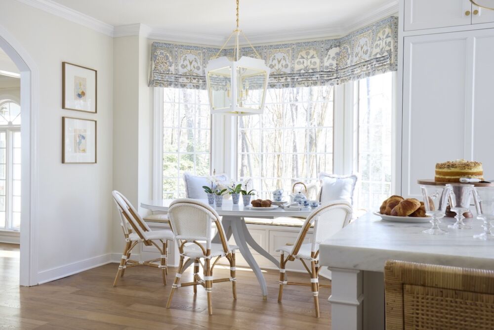 Breakfast are with large white lantern light fixture over table in bay window.
