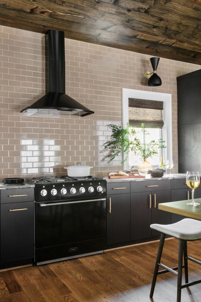 Kitchen with black cabinets and lighting fixture against tan subway tile wall.