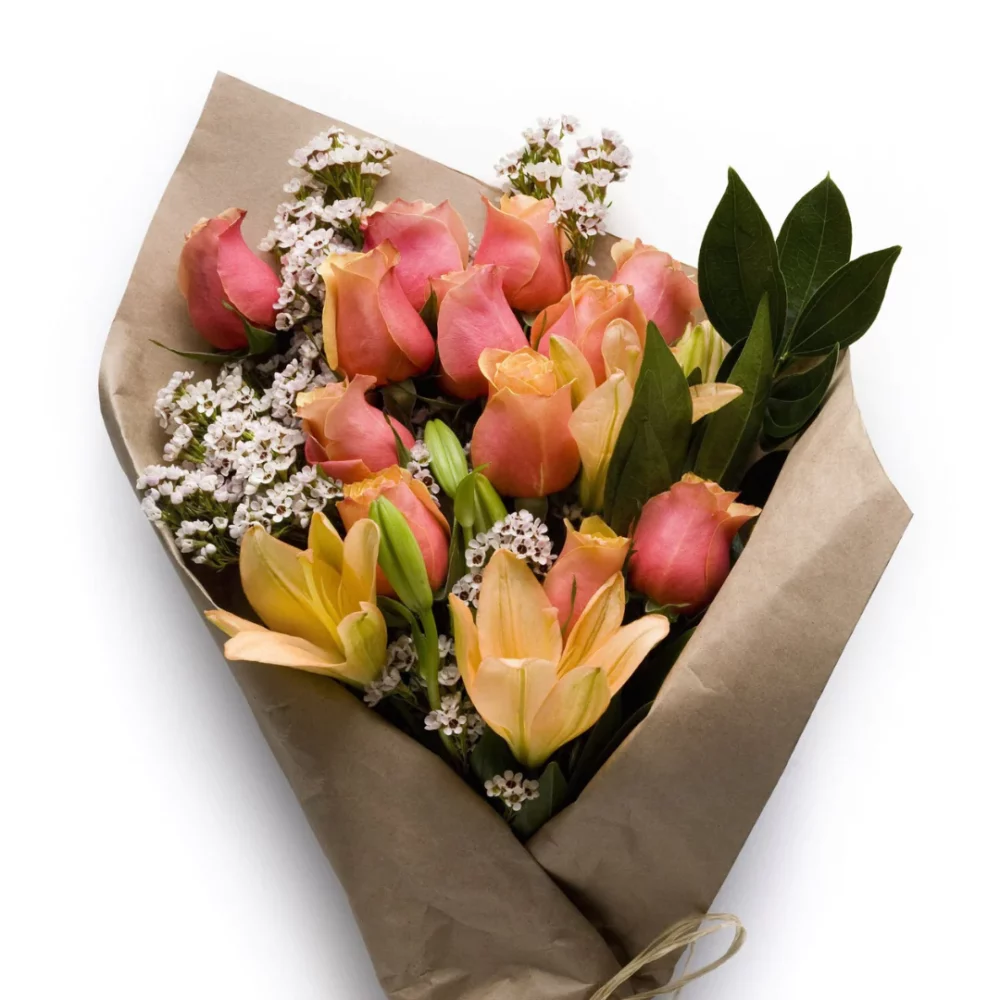 Coral tulips and yellow lilies are wrapped up in a paper bundle.