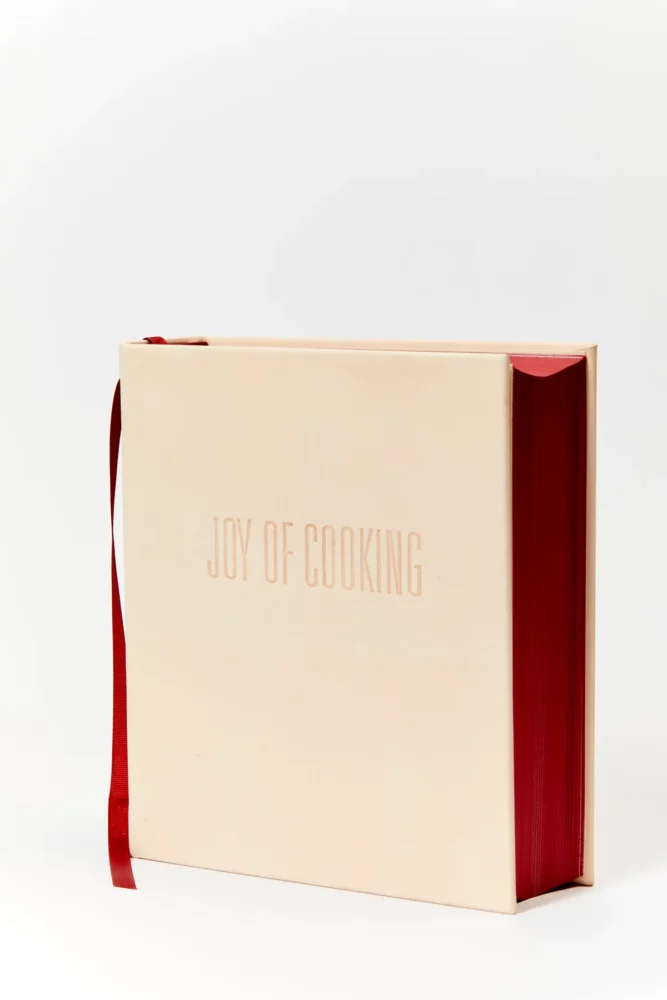 A leather bound Joy of Cooking by Julia Child with red pages.