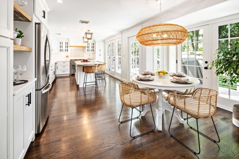 Sunlit kitchen with traditional lantern pendants over island and open, woven statement light over breakfast table.