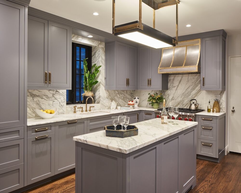 Recessed lighting can be discreet when they are flush to the ceiling and put on dimmers. Lisa Frantz used a bold brass light square fixture over the island that complements the range hood.