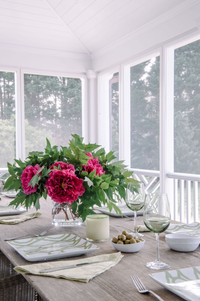 Hot pink peonies dominate a screened in table.