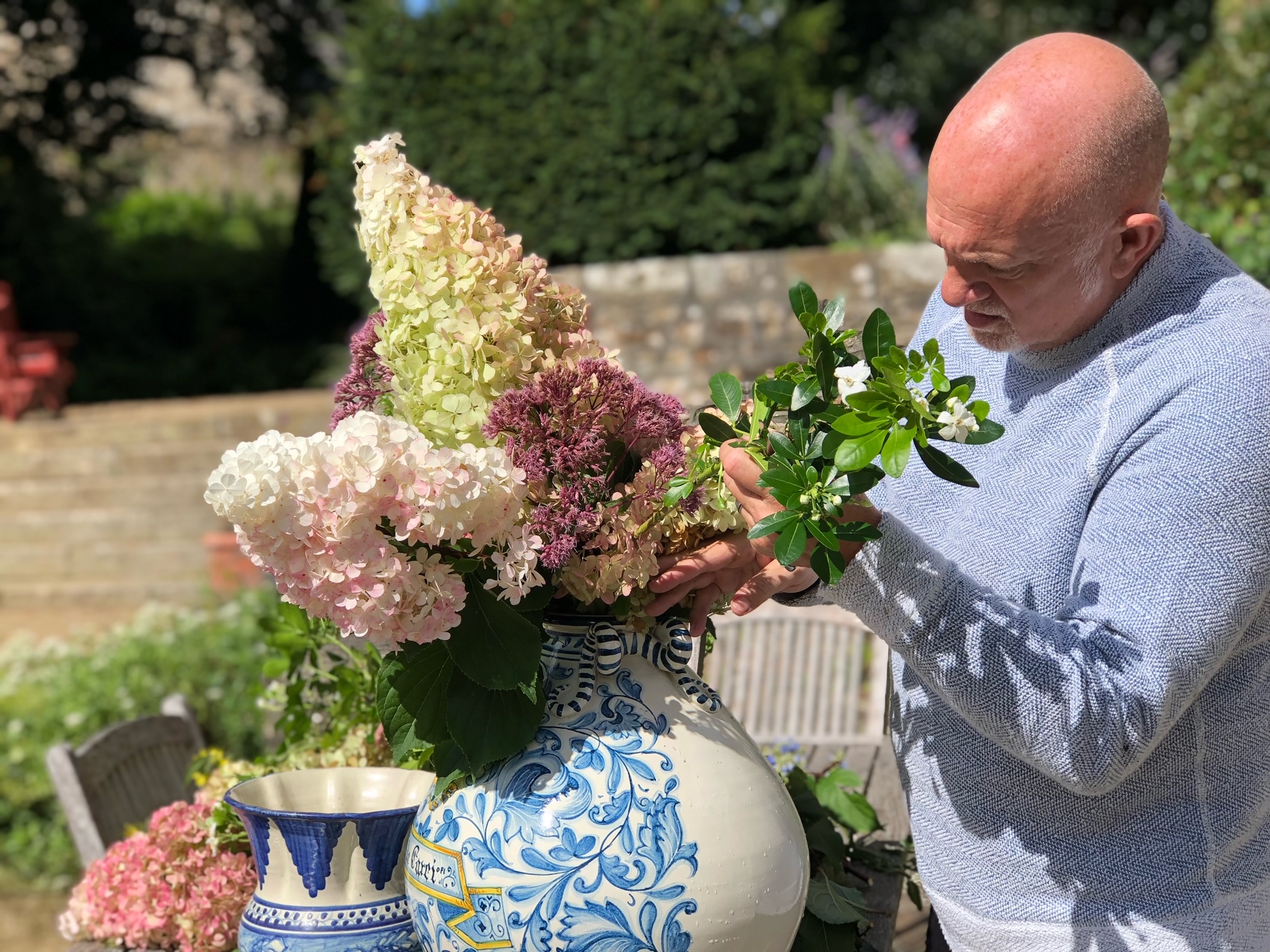 Jamie Merida adjusts pink and white cone hydrangeas in a blue and white chinoiserie vase.