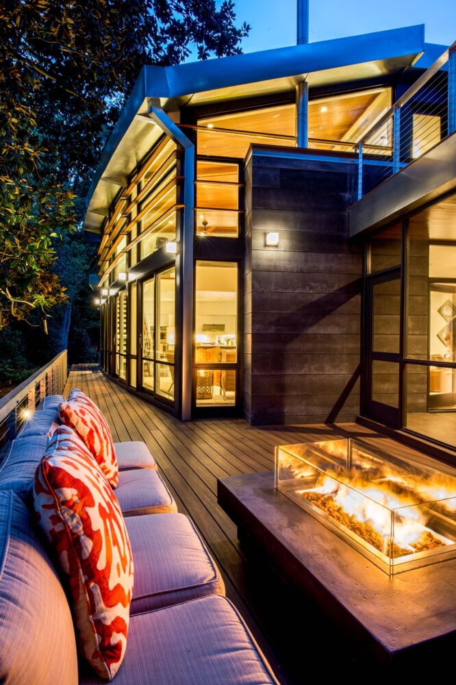 A cozy fire lights up an outdoor space of a modern home.