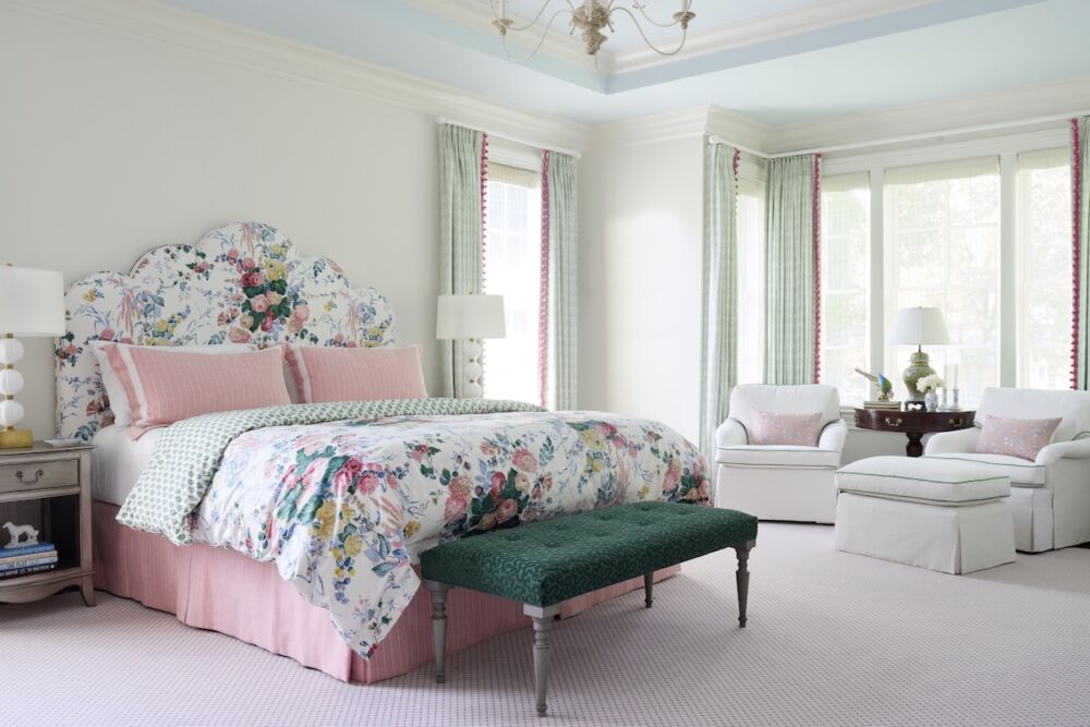 Pprimary bedroom with a classic chintz-covered headboard and duvet accented with soft pink and dark green tones.
