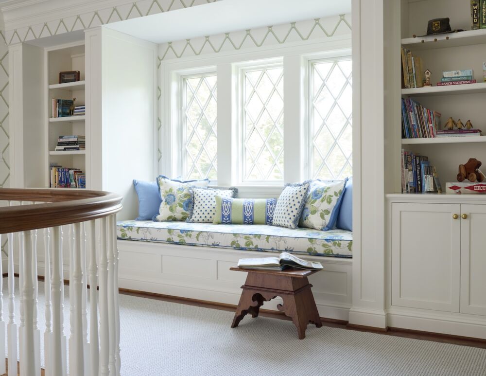 A reading and lounging nook where the homeowner can curl up and read to her grandchildren, filled with a mélange of pretty prints for the pillows and cushion.