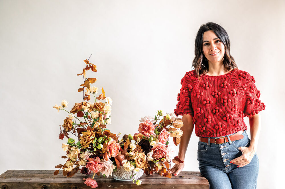 Maria Maxit stands proudly next to her fall inspired centerpiece in a red pom pom shirt.