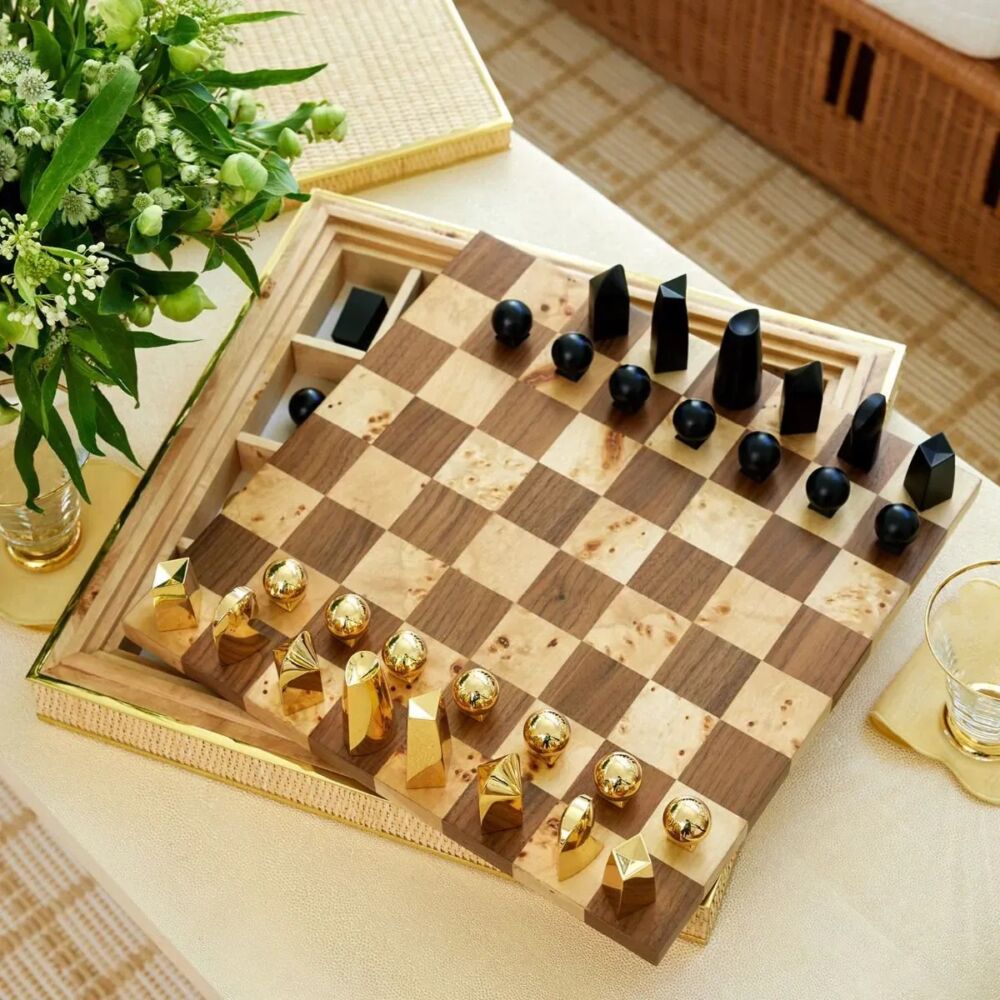 Aerin Colette cain chess set on tabletop with green and white flower arrangement