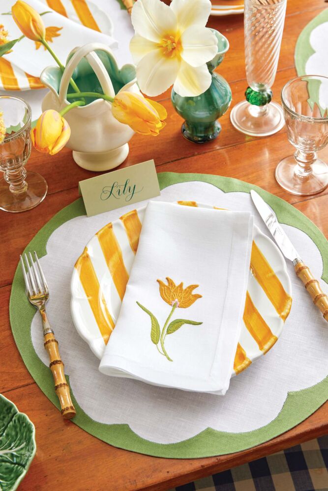 Table setting in green white and good, with yellow tulip napkin.