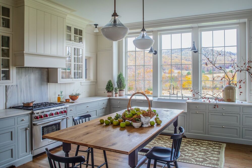 Country kitchen with view of autumn color on hills. Farm table used in place of an island.