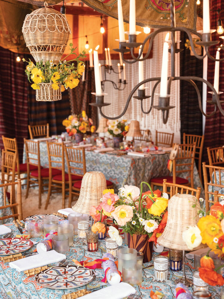 Bright yellow flowers sit on a table with rattan lamps and a bright blue floral patterned tablecloth.