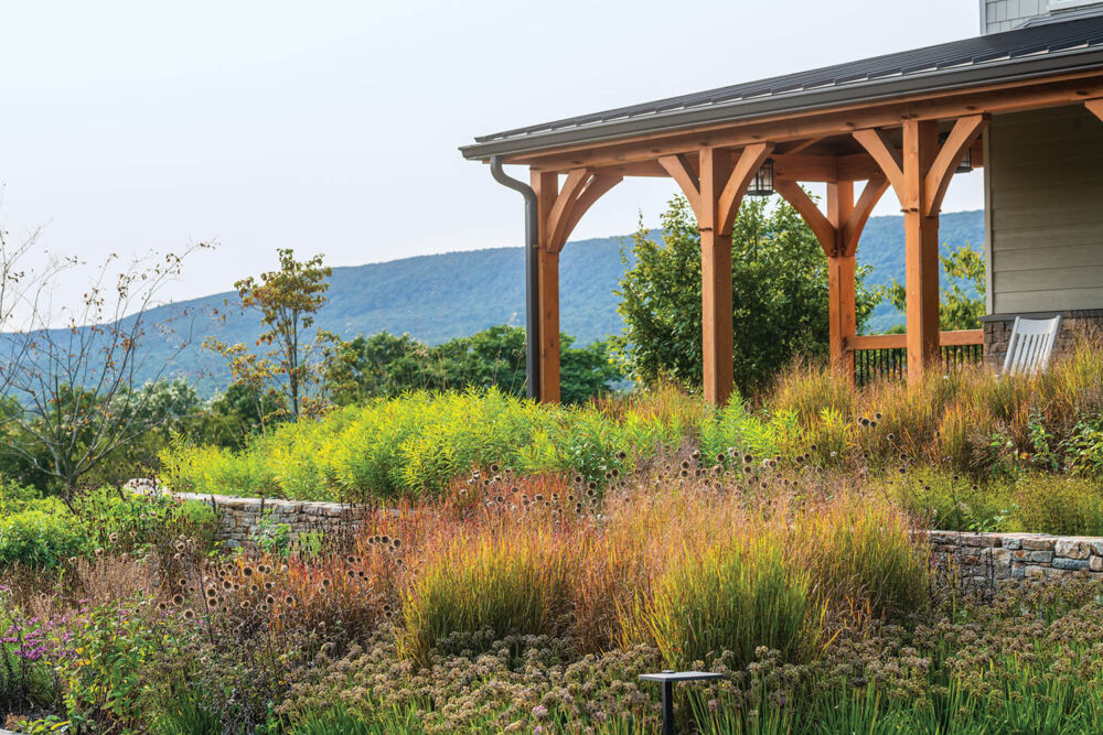 The colorful grasses come all the way up to porch that has wooden beams and corbels.