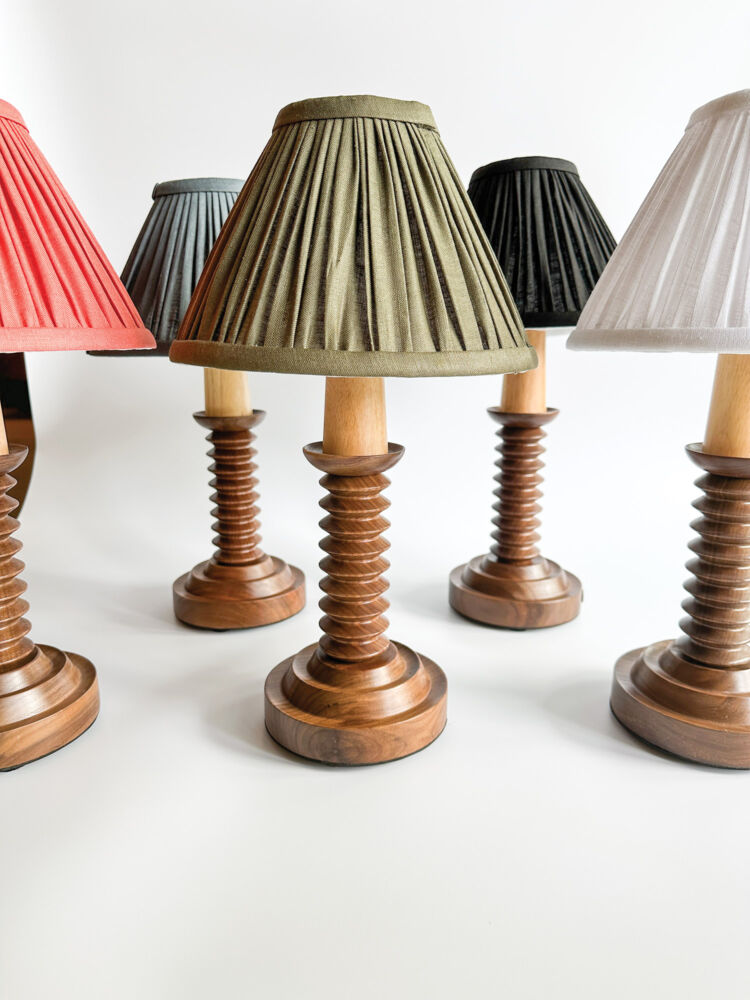 Green, black, pink, grey, and white lampshades sit atop wooden bevelled bases.